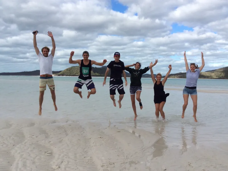 a group of people standing on top of a sandy beach